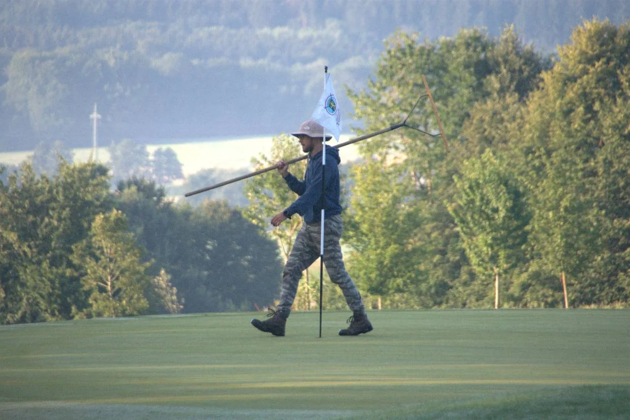 Greenkeeper z grabiami podczas pracy na polu golfowym